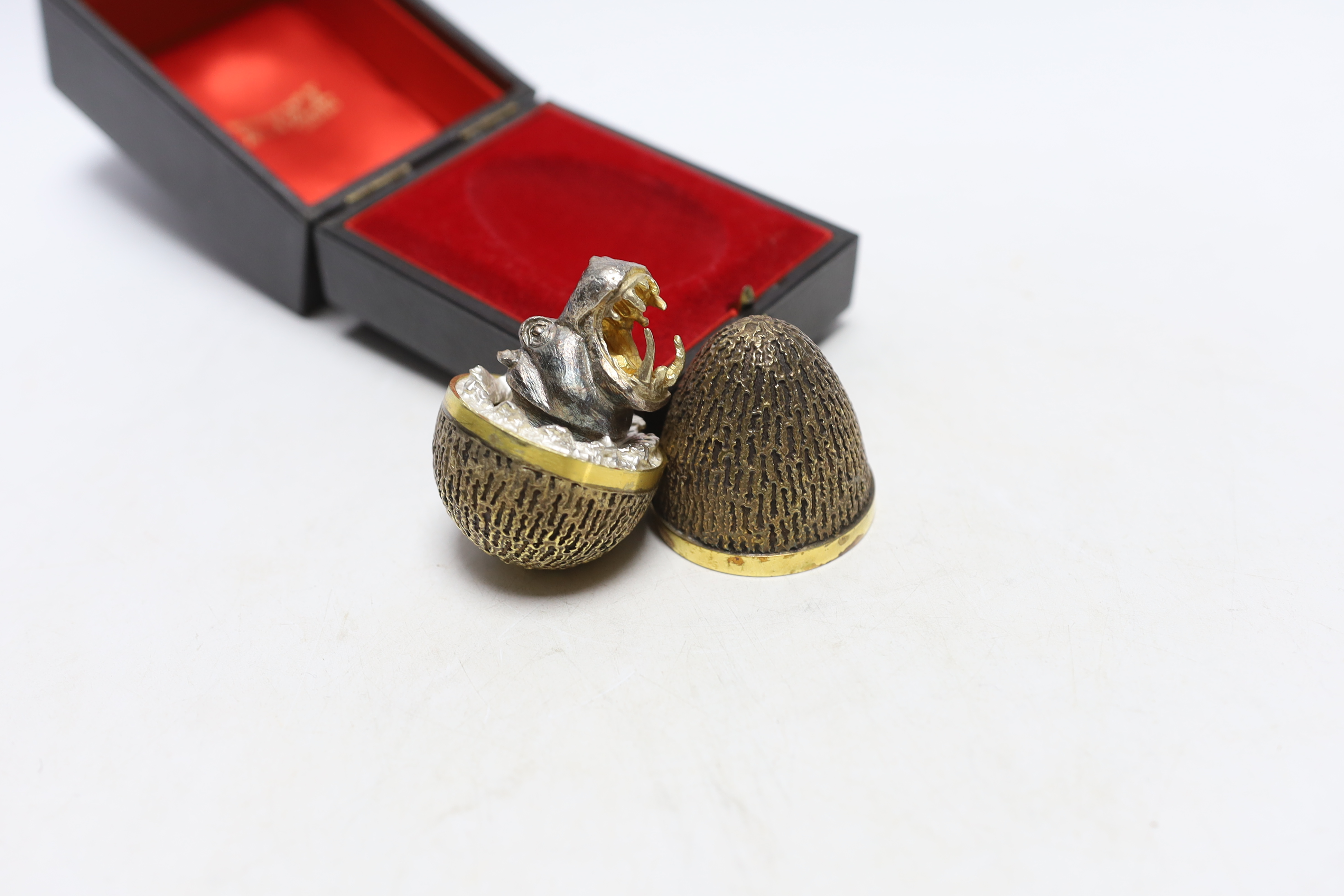 An Elizabeth II silver gilt surprise egg, by Stuart Devlin, London, 1973, numbered 223, opening to reveal an open mouthed hippopotamus, 72mm, in original Devlin box.